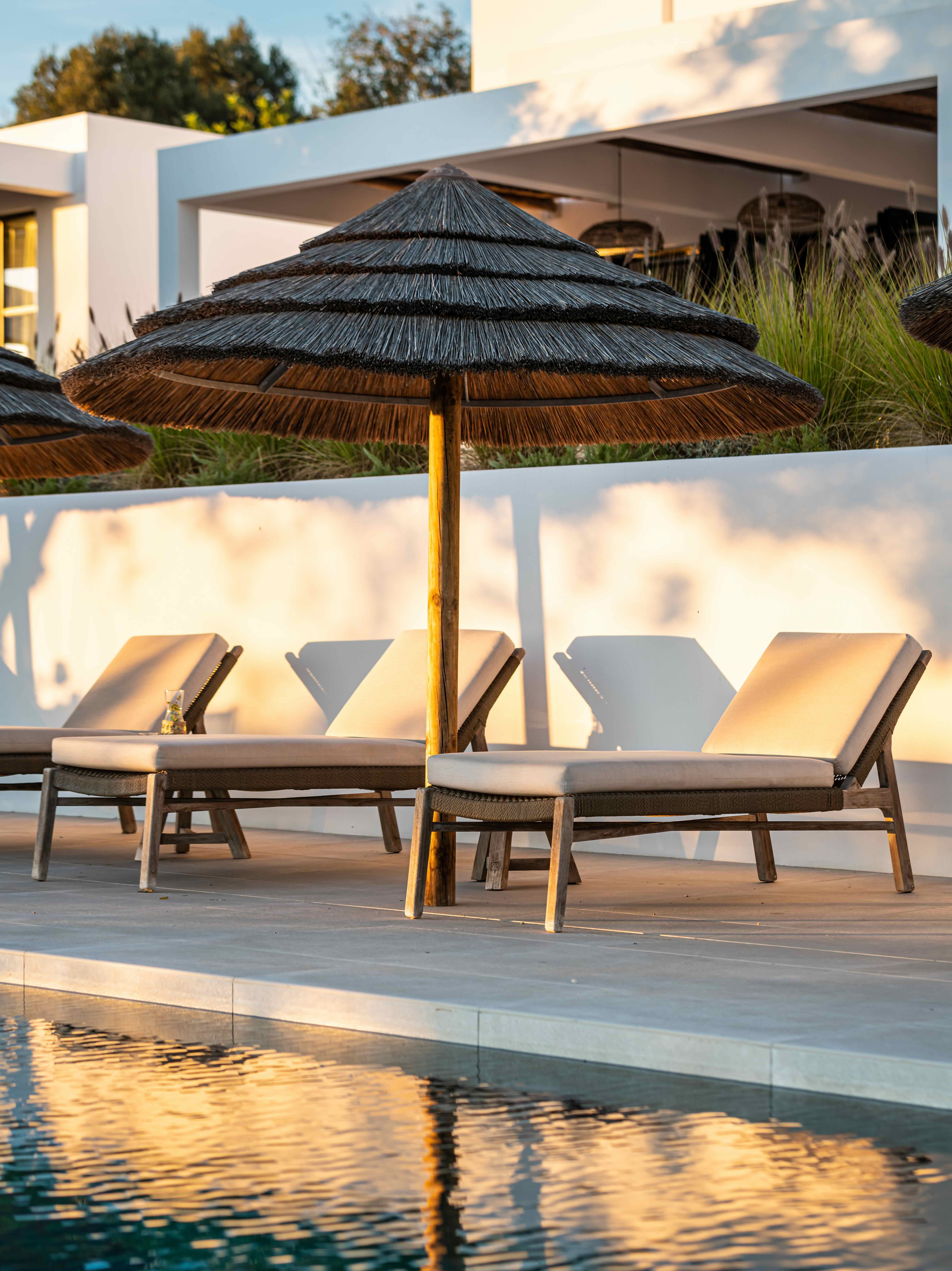 Poolside lounge chairs and bespoke outdoor furniture design at a luxury holiday villa in Portugal, featuring a calm architectural setting with natural materials by I+Y Interior Architecture Studio.