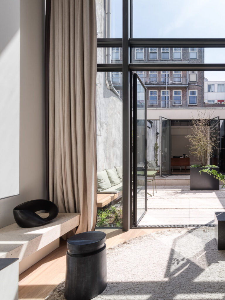 Glass facade view from the living room looking towards the urban inner courtyard, connecting interior space with the city garden, designed by I+Y
