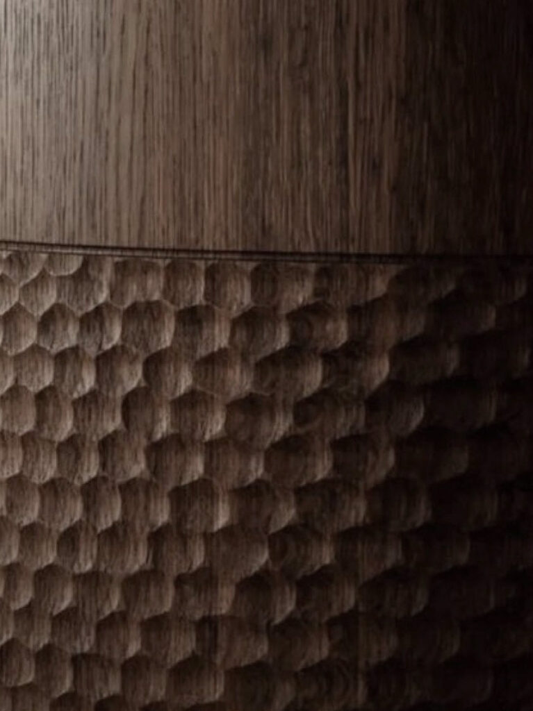 Close-up detail of custom-made wooden furniture featuring a hand-carved textured surface and natural oak grain.