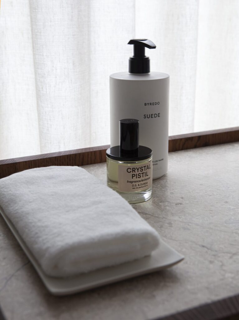 Bathroom styling detail in City Apartment Amsterdam with natural stone surfaces, soft textiles and subtle daylight, emphasizing tactility and material calm.